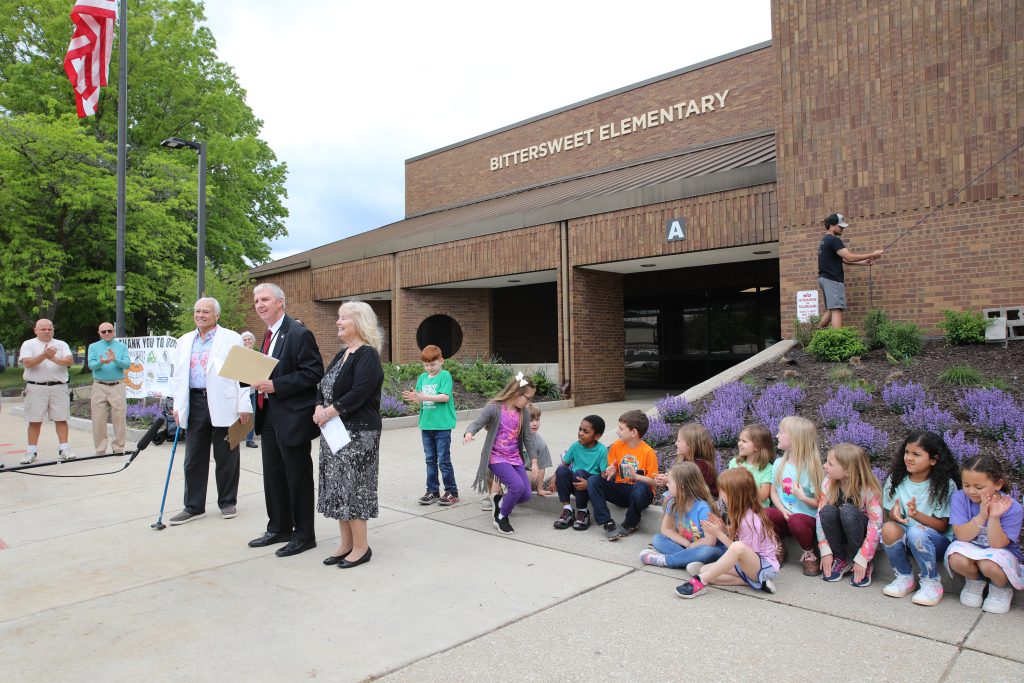 A group of people, including adults and children, gathered outside