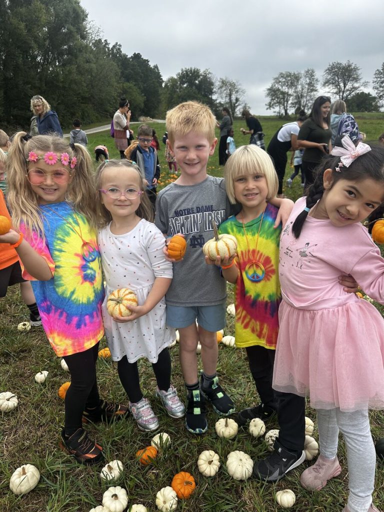 Five children in a field of pumpkins, posing for a picture.