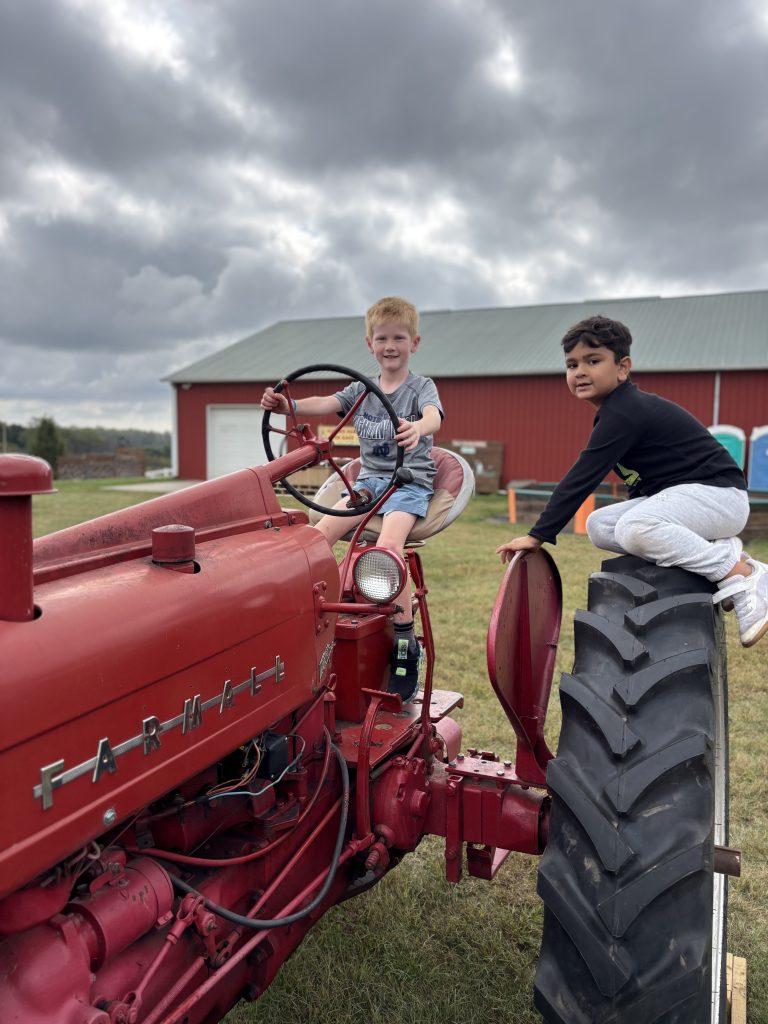 Two people sitting on a red tractor in a field.