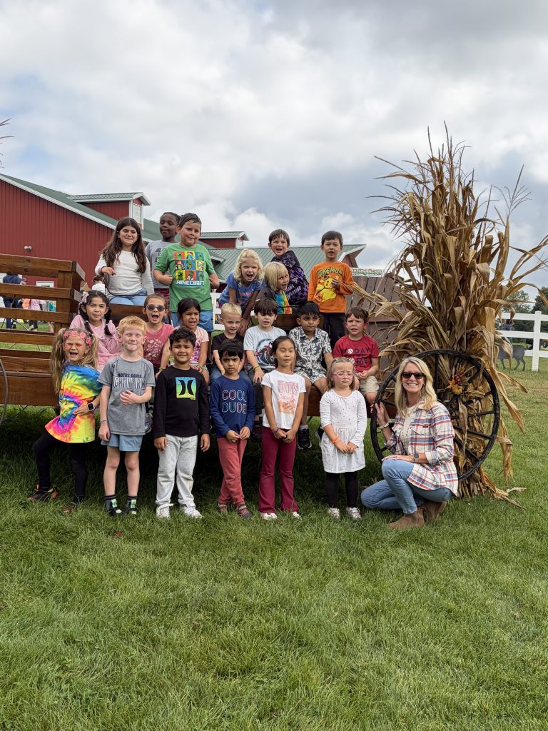 Group of people posing in front of a corn maze on a farm.
