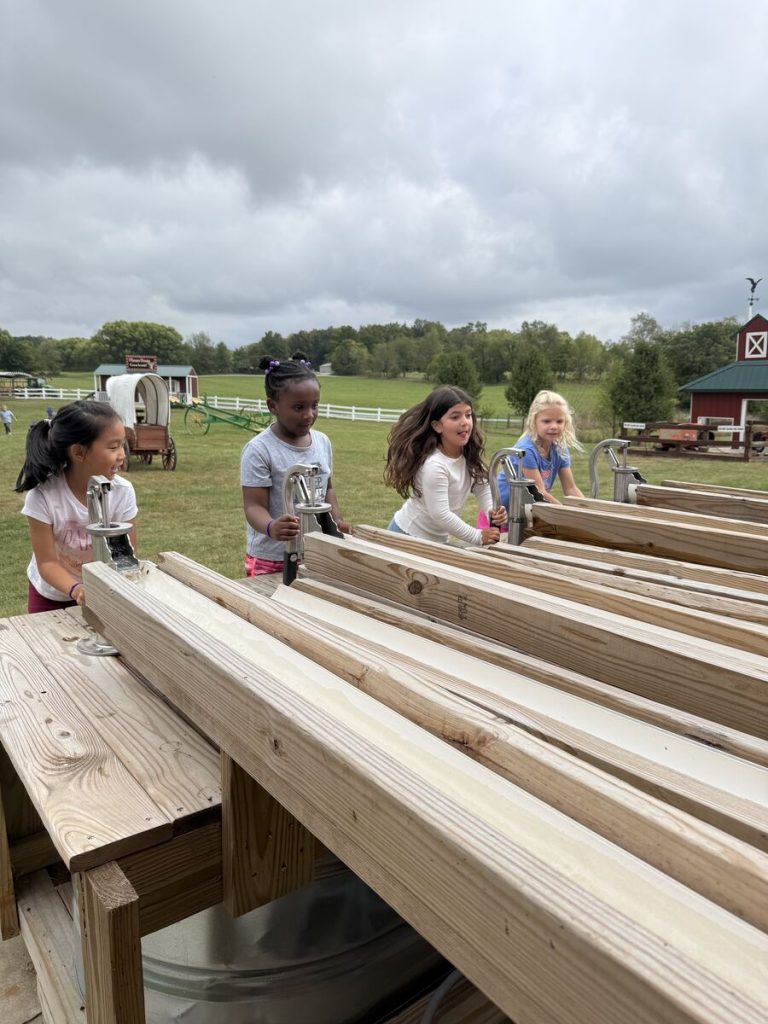 Children playing on a wooden structure in an outdoor setting.