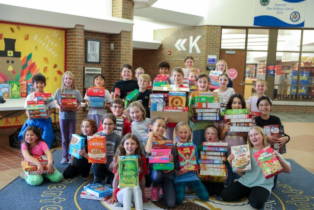 Student leadership group poses with cereal boxes.