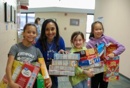 Students and principal pose with cereal boxes for a picture.