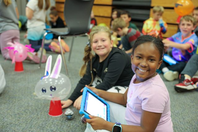 students smiling holding an iPad