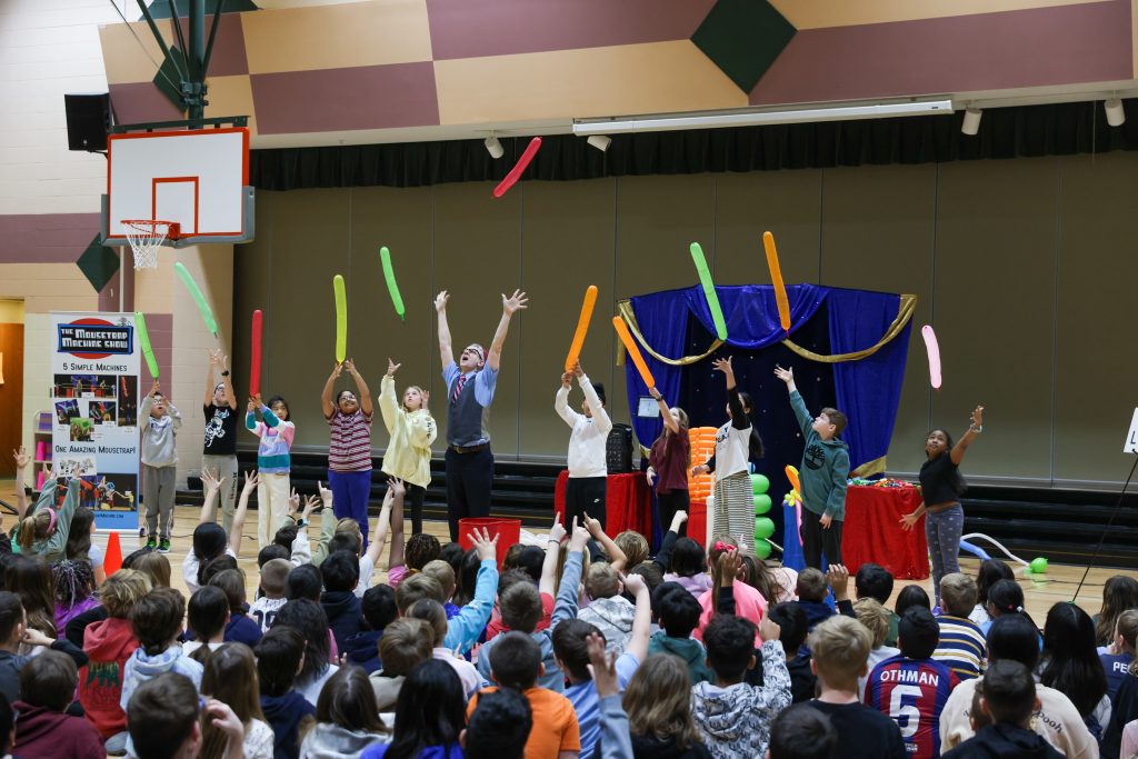 Children performing in gymnasium with colorful streamers.