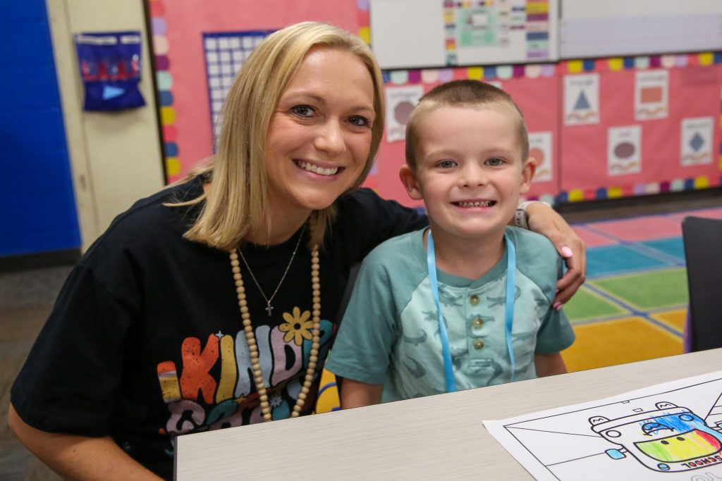 Teacher in kindergarten t-shirt with smiling kindergarten student