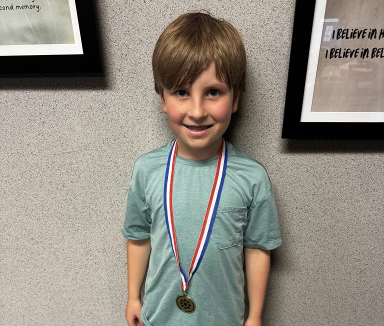 Young boy wearing a medal around his neck.
