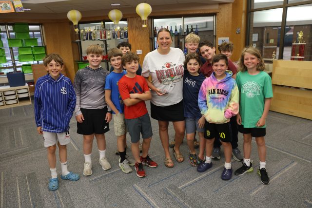 Woman in white shirt standing with group of children posing for picture.