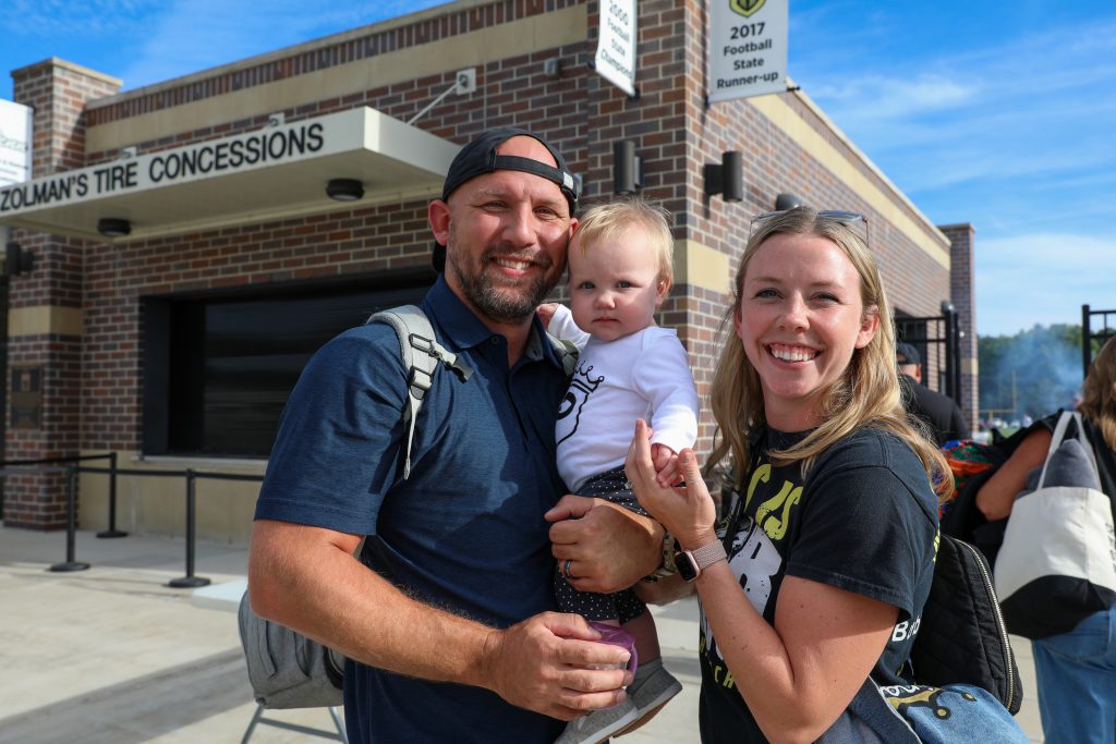 A family posing in front of a building with a sign that reads 'Tire Concessions'.