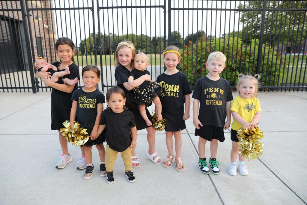 Young cheerleaders posing in front of a fence.